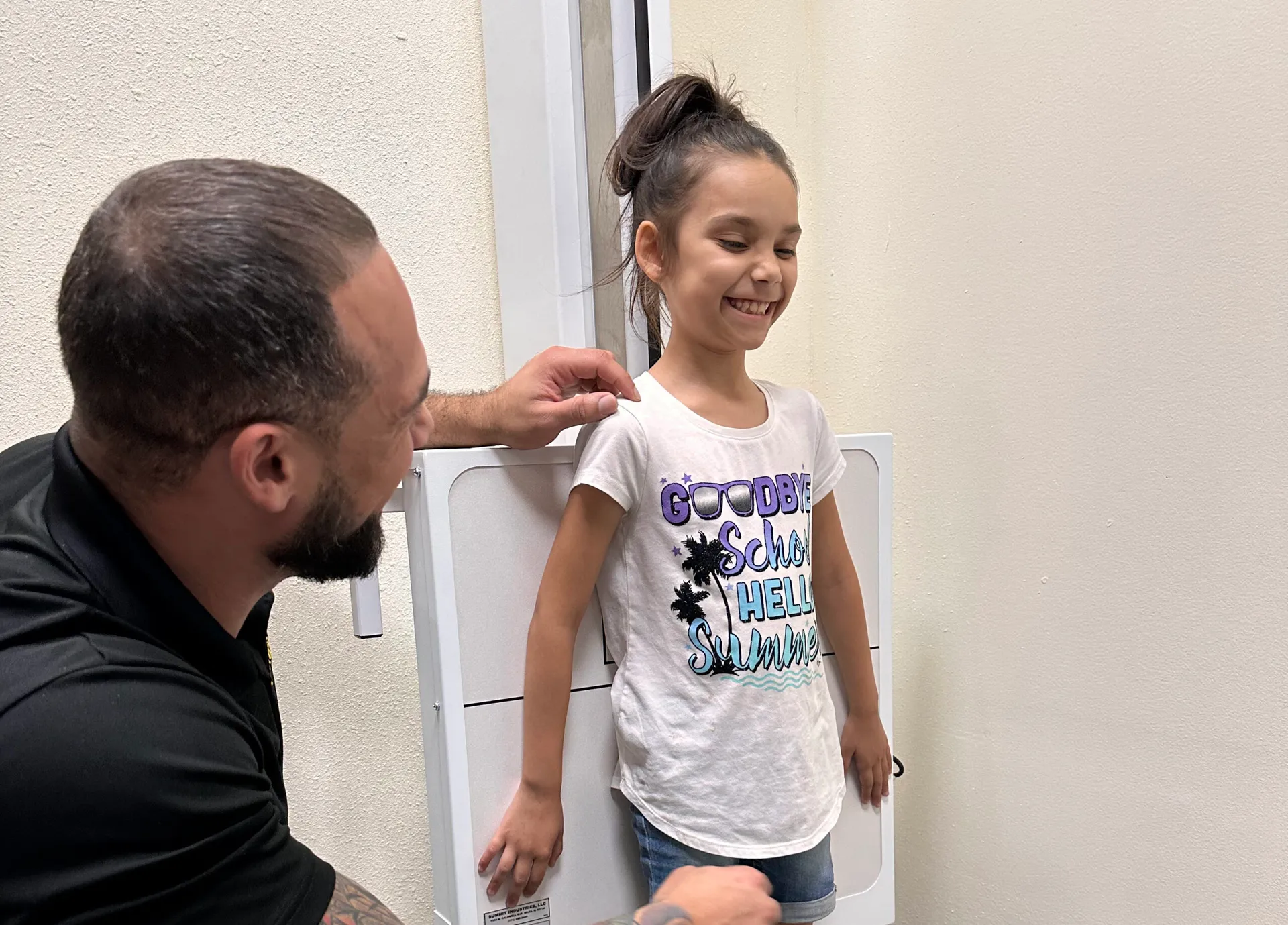Dr. Junior placing his hand on a smiling girl's shoulder to position her for an X-ray.