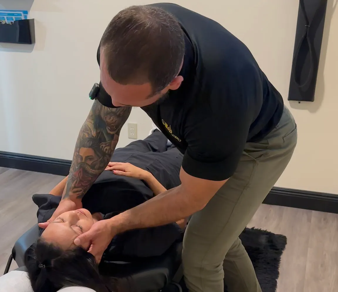 Chiropractor adjusting the neck of a woman lying face up on a chiropractic table.