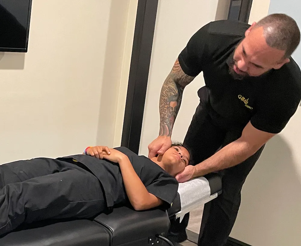 Dr. Junior adjusting the neck of a young patient lying face up on a chiropractic table.