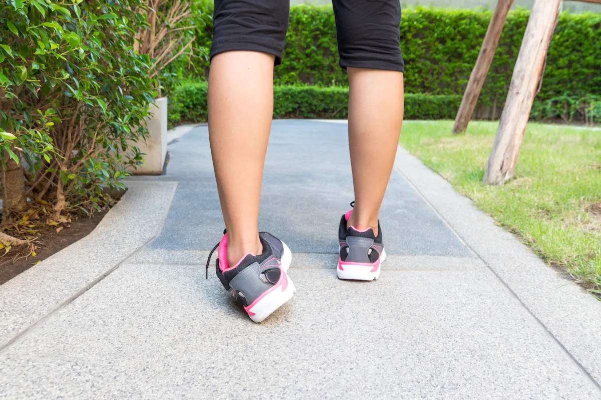 Person in sneakers rolling their ankle while walking on a paved path.